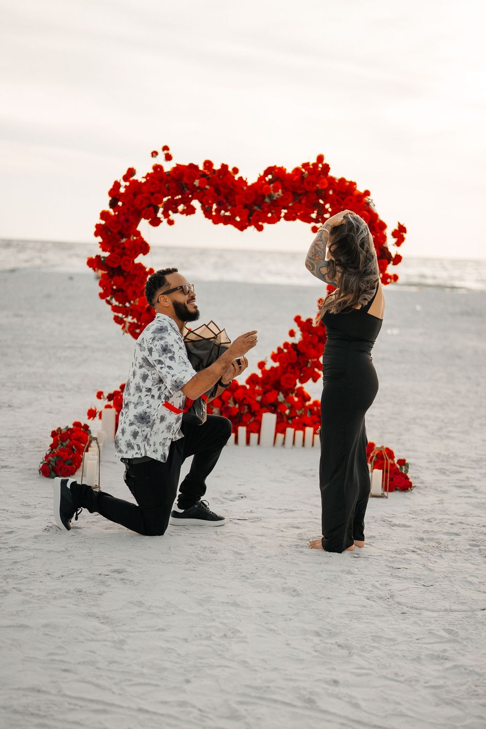 Romantic beach proposal in Tampa Florida with red heart floral arch and roses