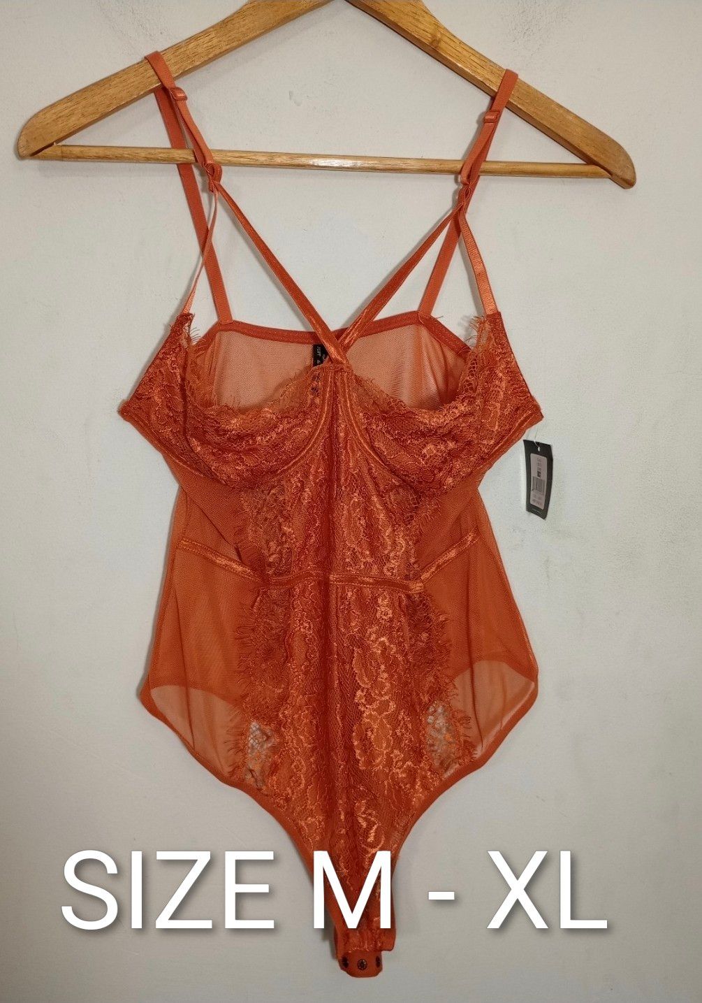 Orange lace and mesh bodysuit size M-XL displayed on hanger, featuring strappy design and underwire cups with tags attached.