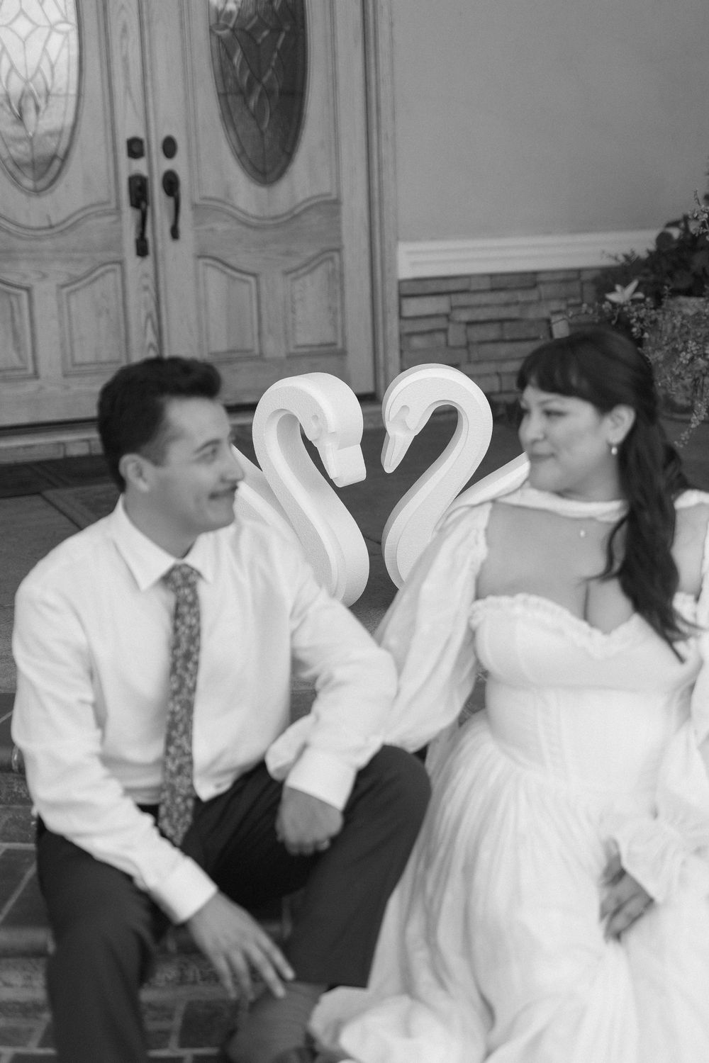 Black and white photo of a couple with a swan behind them.
