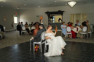 Bride and groom seated on dance floor at elegant wedding reception with guests dining in decorated banquet hall.