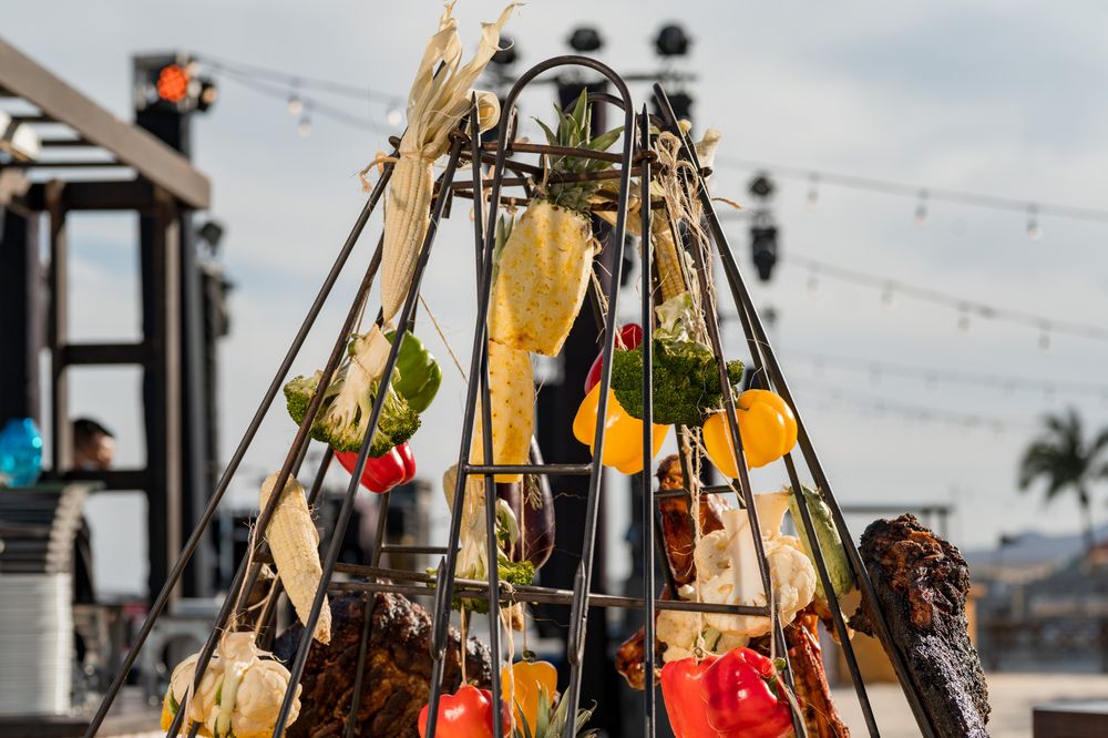A decorative tower display of fresh colorful vegetables and corn at an outdoor food festival event.