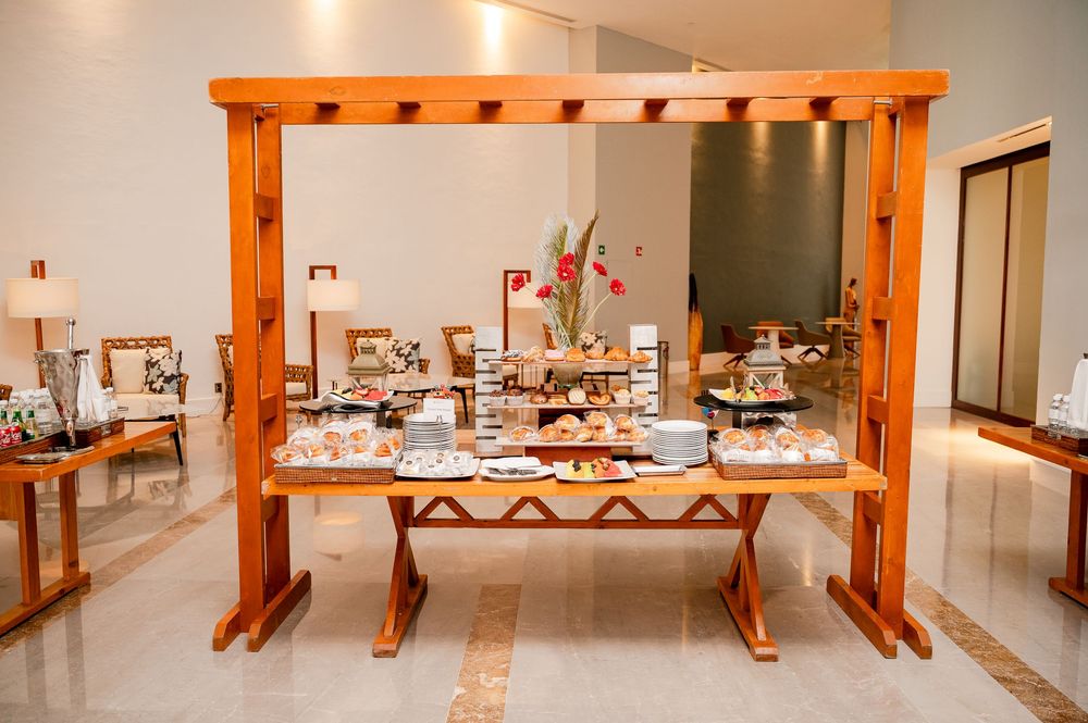 Elegant wooden pergola buffet table display with food and decorations in a bright modern interior space.
