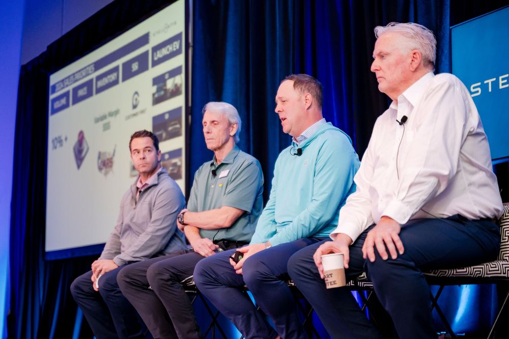 Four male panelists seated on stage during a Stellantis corporate conference presentation.
