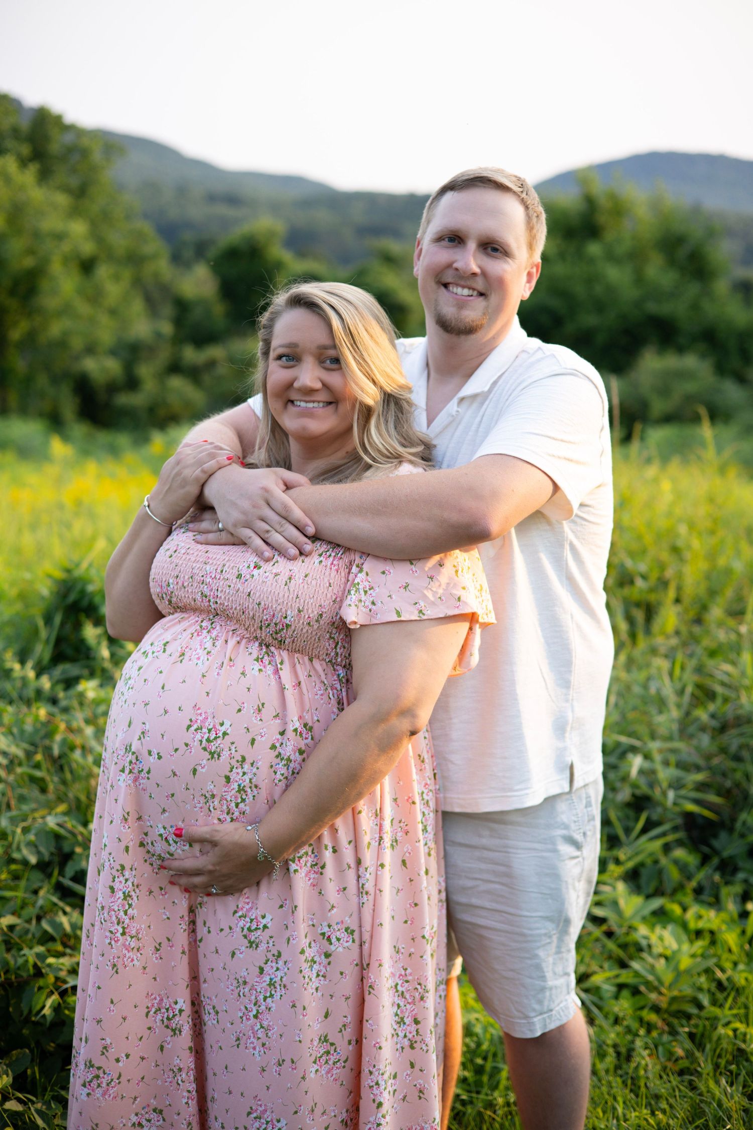 A couple hugging during maternity photos in a field in Amherst, MA