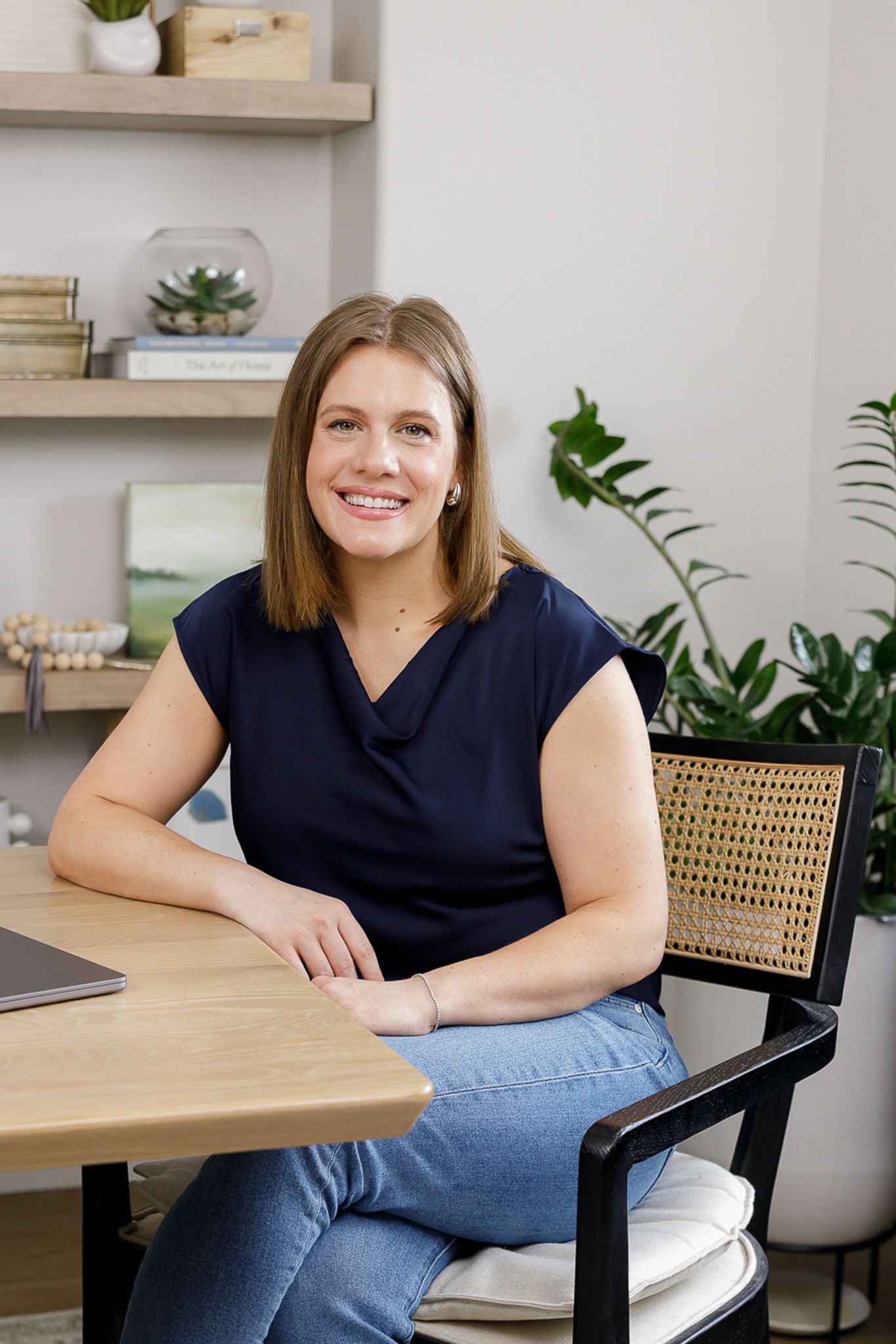 female real estate agent lifestyle headshot in Auburn, WA sitting in dining room chair with laptop on table smiling at camera