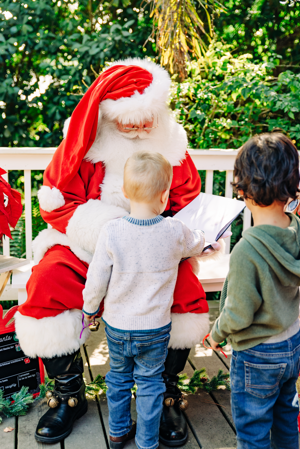 Lake Worth Beach Santa experience with Santa Claus sharing his Christmas book with two children.