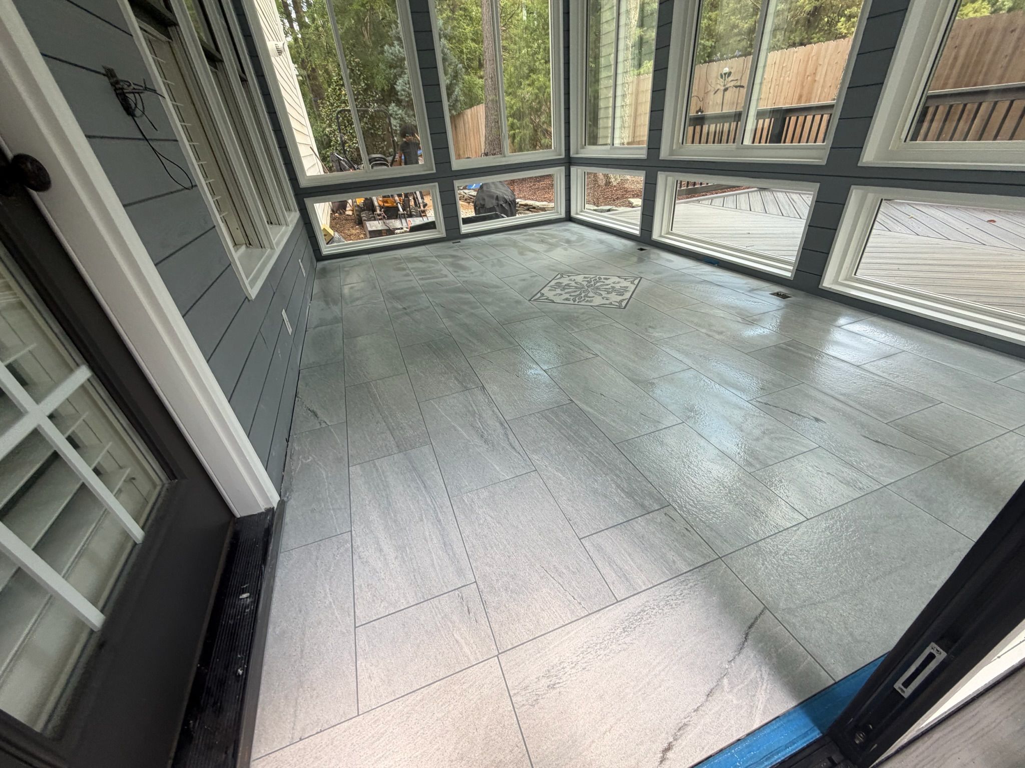 Screened porch interior with large gray stone floor tiles and natural outdoor views.