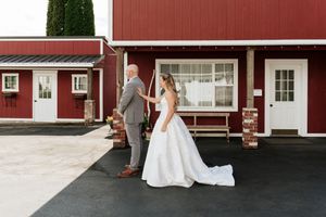 Bride and groom share a first look moment outside a rustic red barn wedding venue.