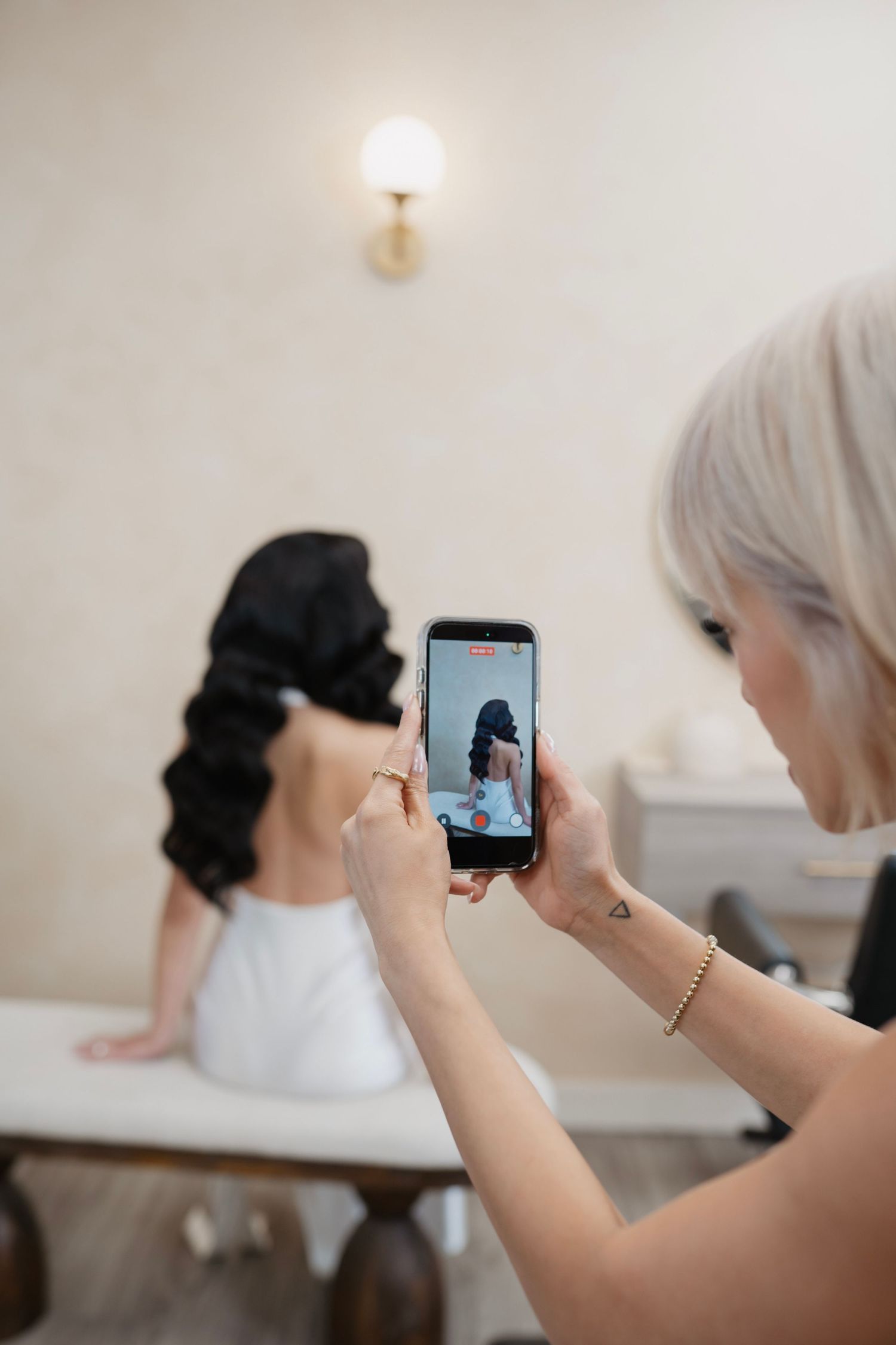 Esthetician in black gloves performing eyebrow threading treatment on a woman lying on a white towel.