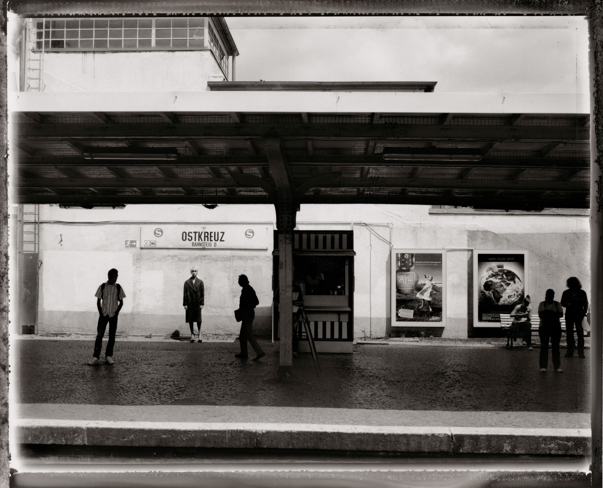 Black and white photo of people waiting at Ostkreuz train station platform in Berlin, Germany.