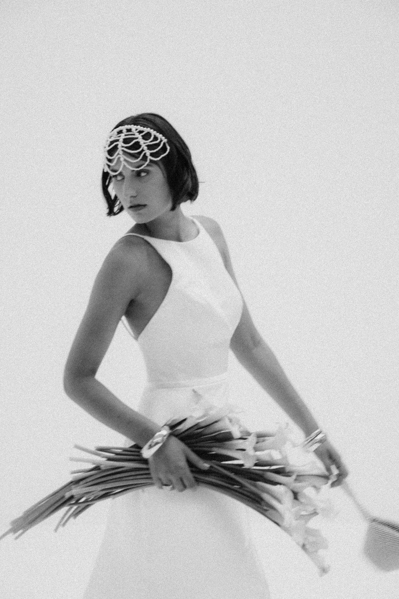 Black and white photo of a bride in a white gown and veil holding a beaded bag.
