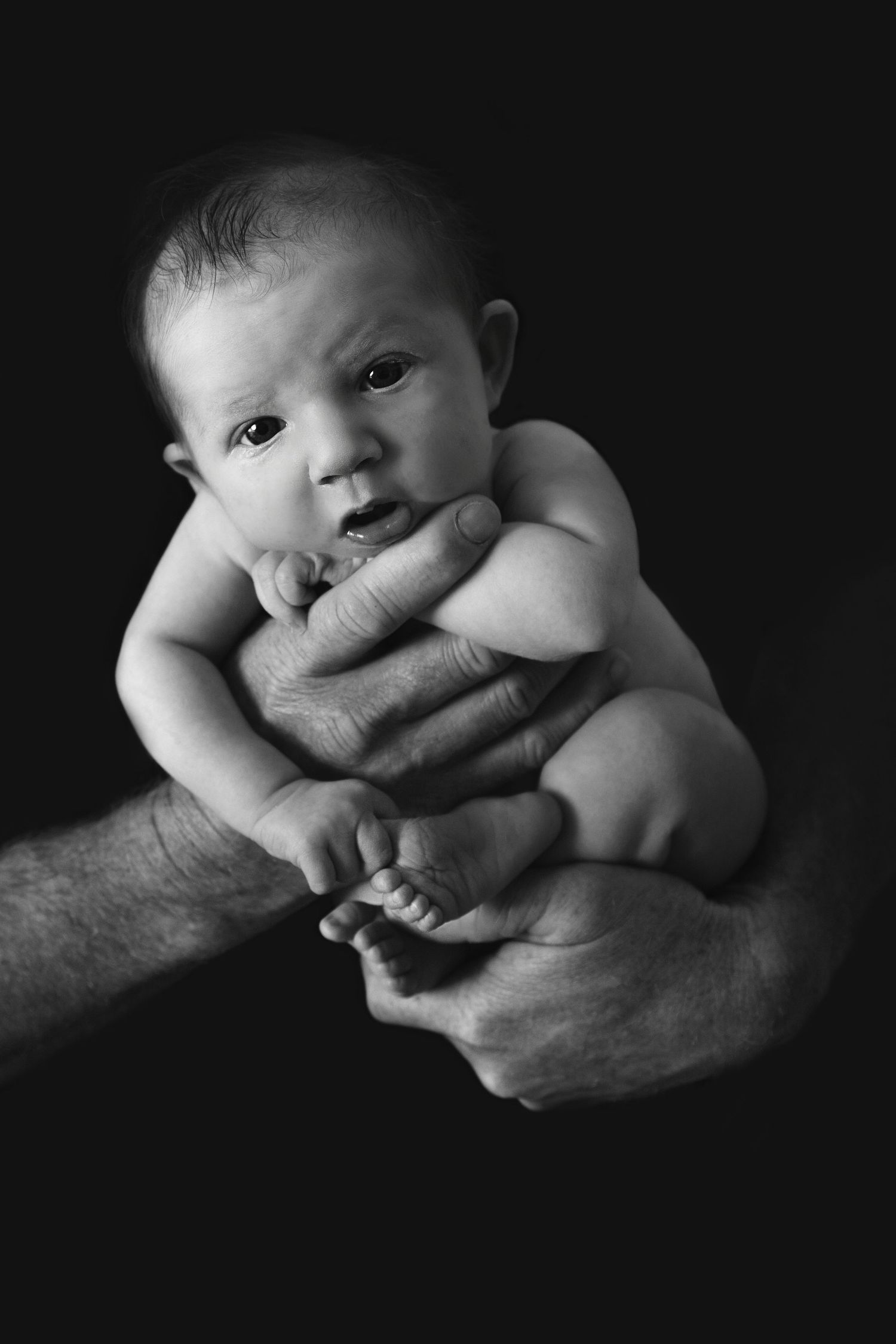 black and white image of a baby girl in her fathers hand at her newborn session Pacific pines