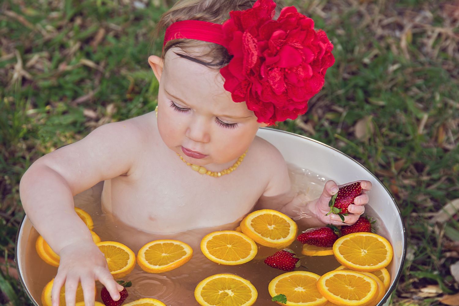 1 yr old girl sitting in a large white bucket for her 1st birthday fruit bath photography session on the