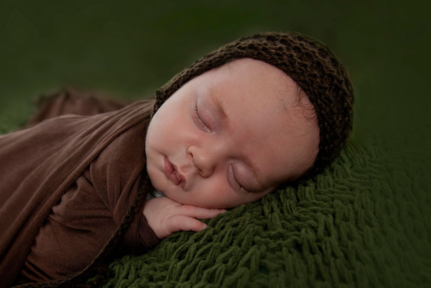 sleeping baby boy on a knitted green blanket at his newborn photography session in Pacific pines