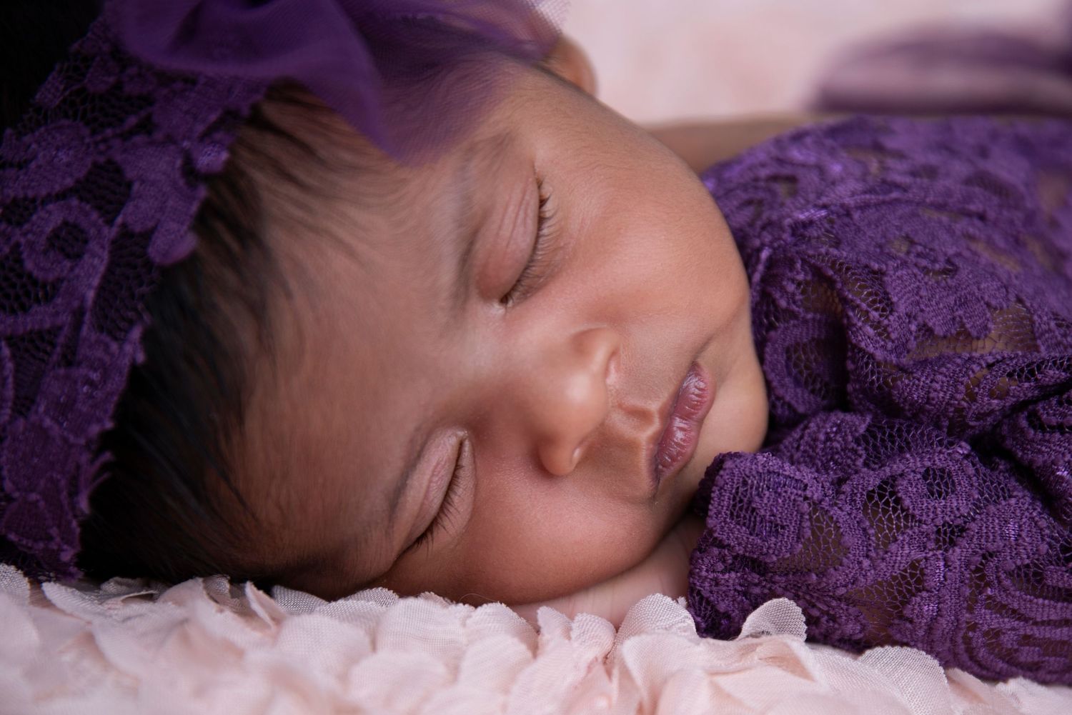 Sleeping newborn baby wrapped in a cream blanket in a Gold Coast studio.
