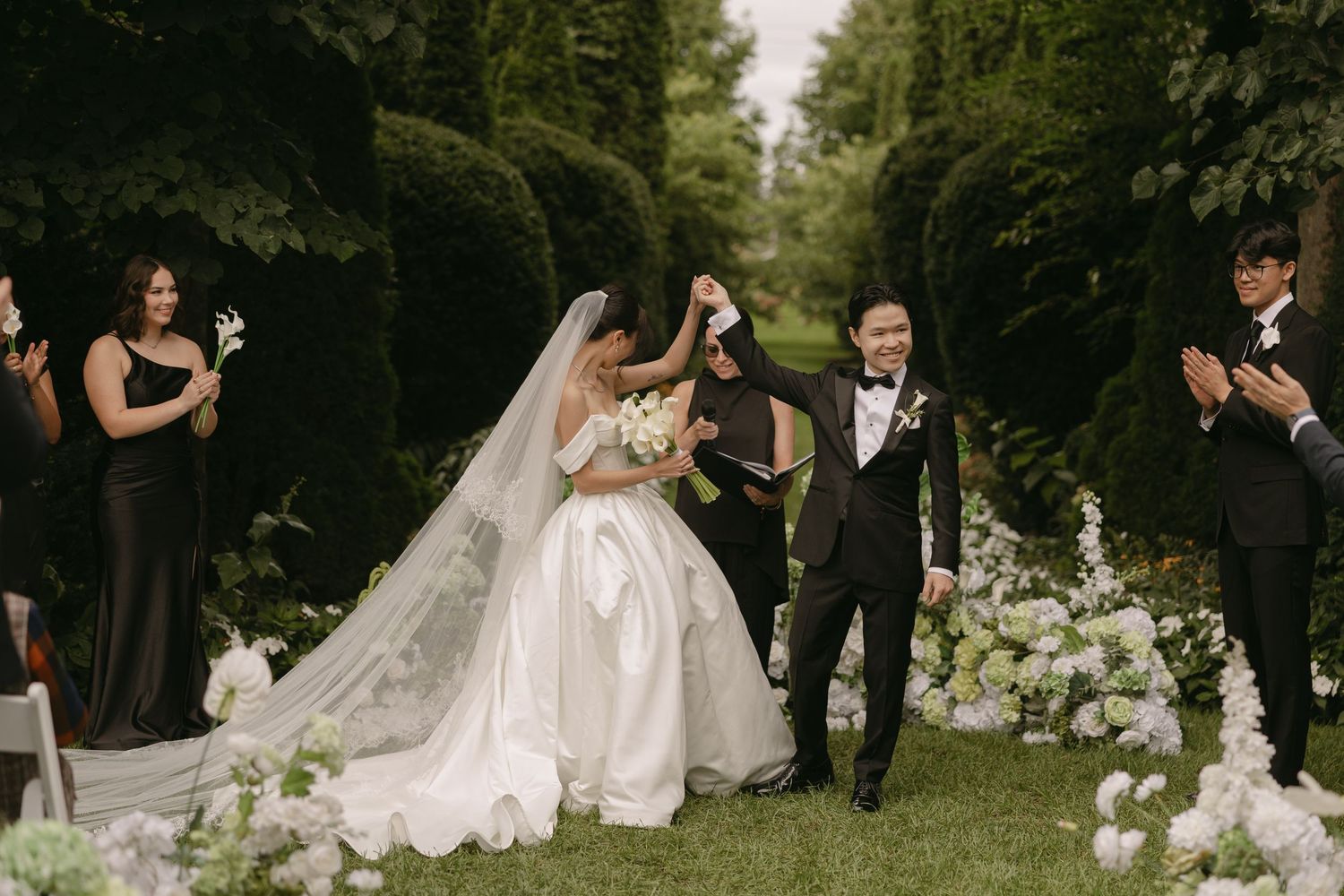 Bride and groom celebrate walking down the aisle at an elegant outdoor garden wedding ceremony.