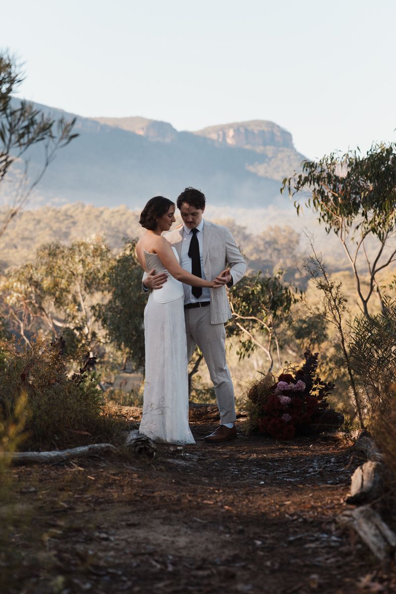 Elopement photoshoot near sydney. Bride and groom share intimate moment during outdoor wedding ceremony with mountain landscape backdrop.