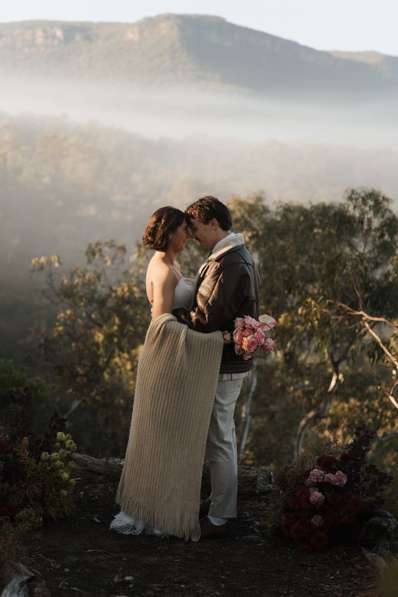Couple embracing at misty mountain overlook during golden hour wedding elopement with lush valley backdrop elopement photoshoot