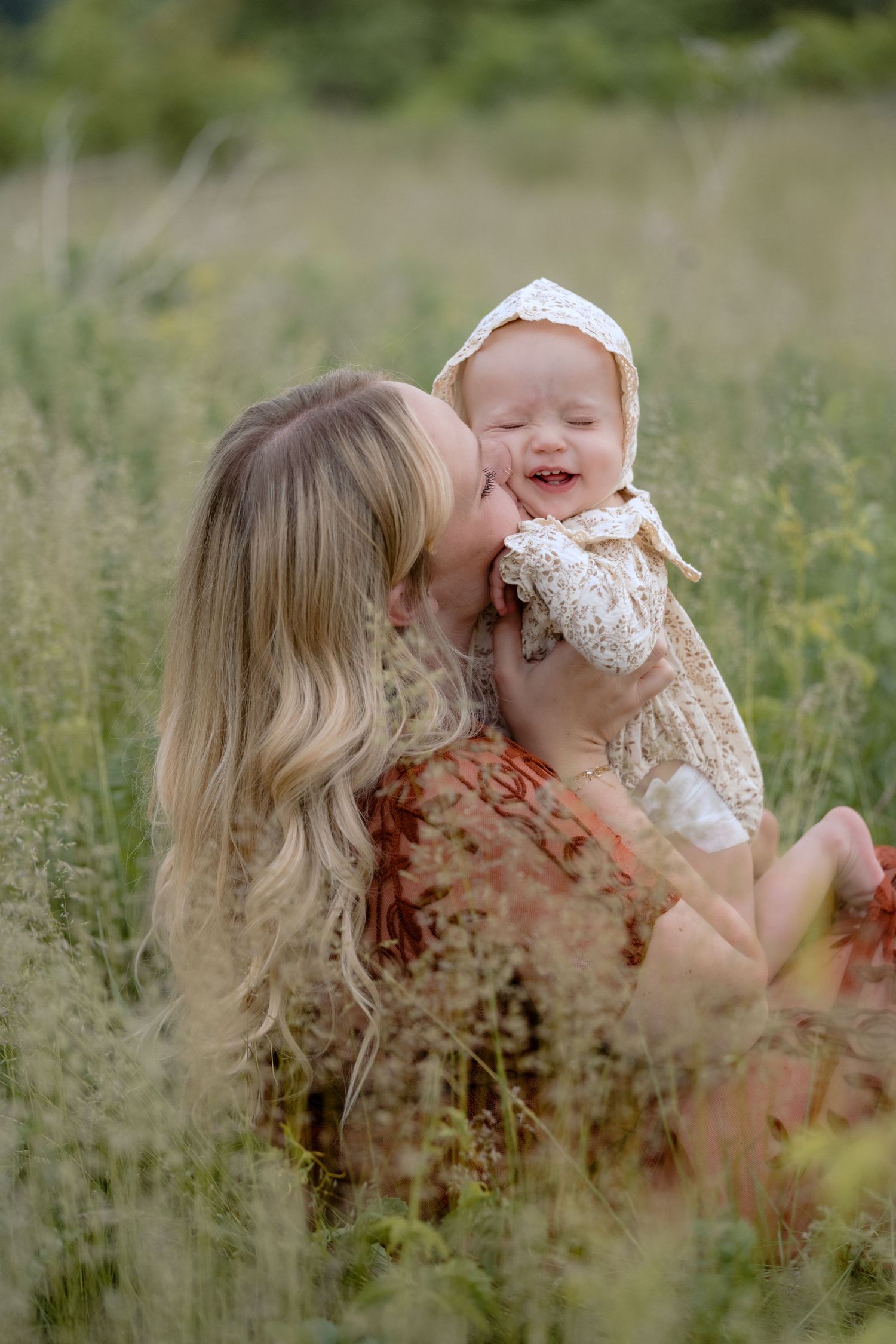 mom kisses baby girls cheeks during outdoor family photos in Hudson, WI.