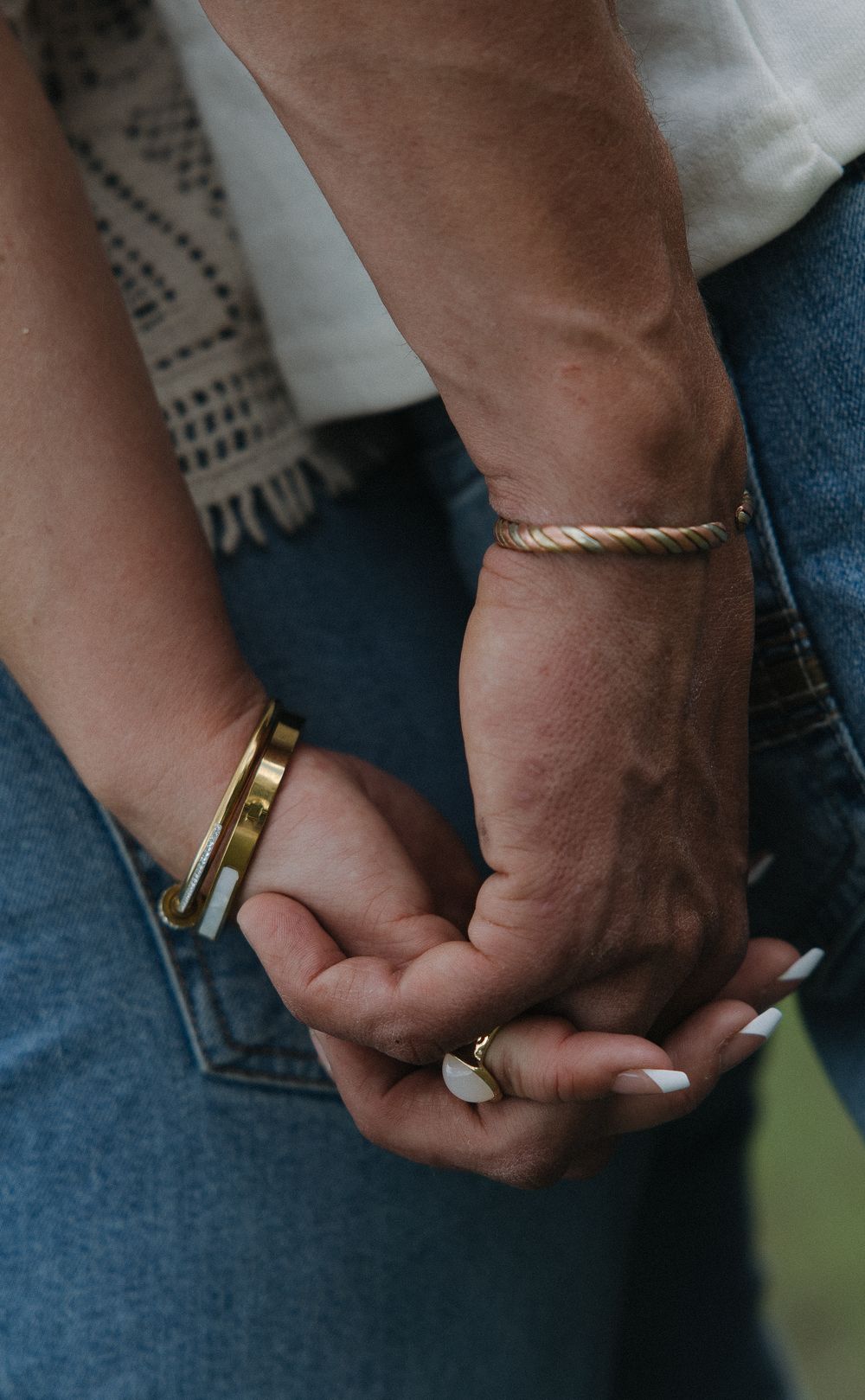 Close-up of couple holding hands wearing gold bracelets and white nail polish near denim jeans.
Great Falls Montana Couples photoshoot, phot