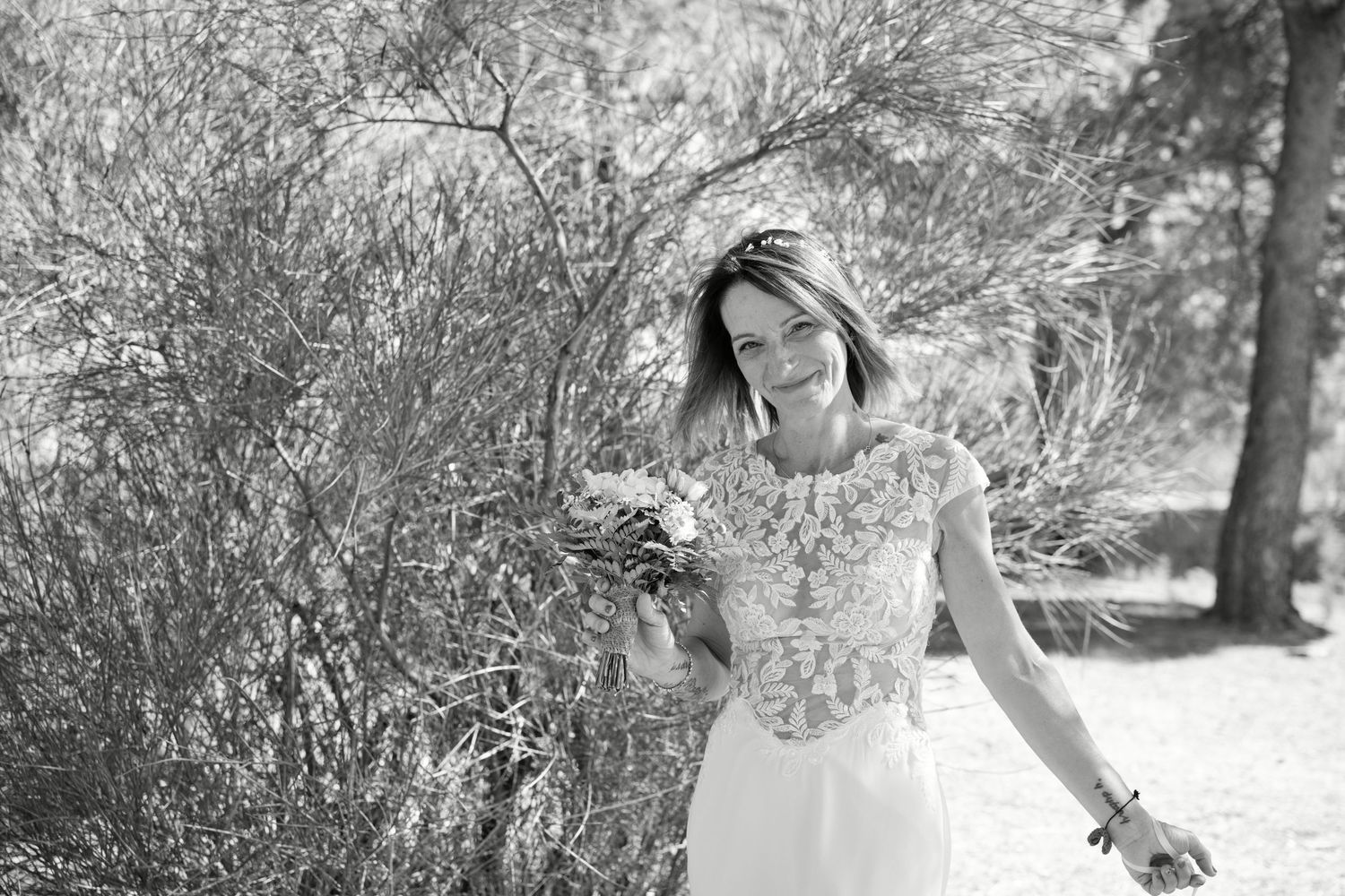 Portrait de Delphine en robe de mariée, son bouquet à la main, photographié en noir et blanc.