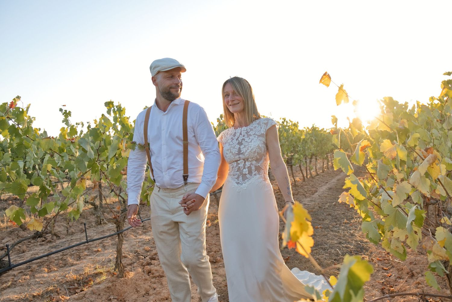 Delphine et Christophe marchent main dans la main entre les vignes de Pourrières au soleil couchant.