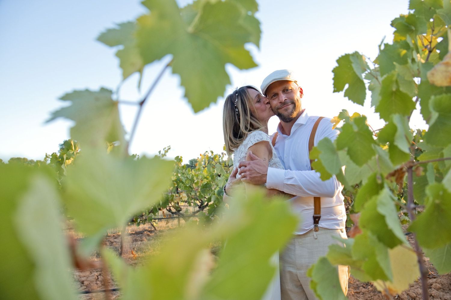 Delphine pose la main sur le visage de Christophe pendant leurs photos de couple dans les vignes.