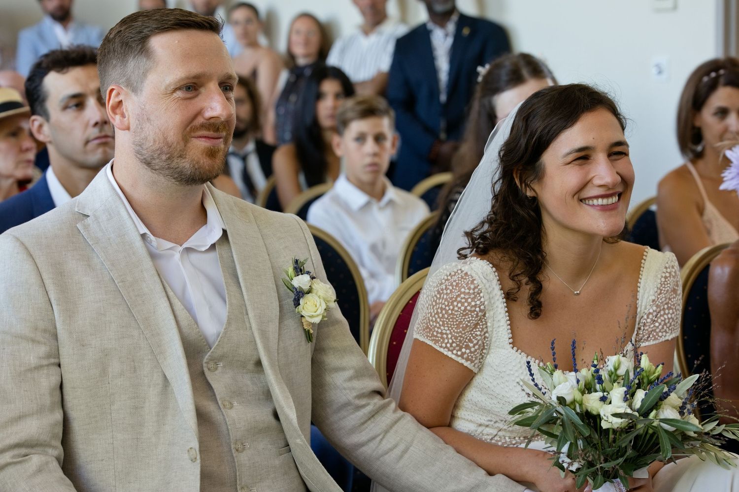 Augustine et Ugo sourient côte à côte pendant leur cérémonie de mariage.