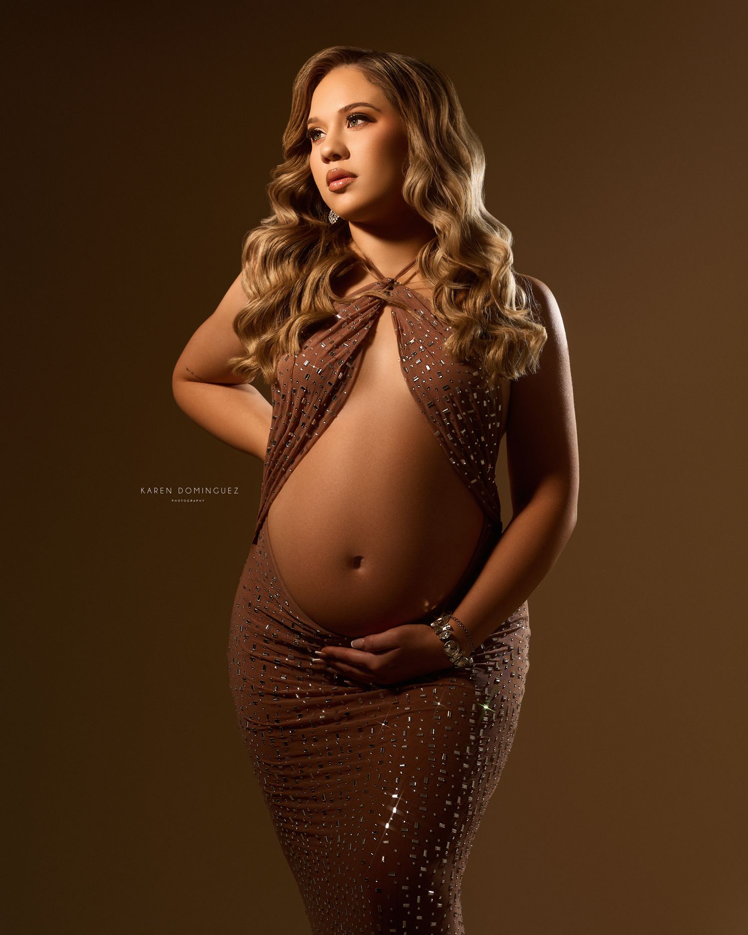 Artistic maternity portrait surrounded by colorful flowers and natural elements in romantic setting.