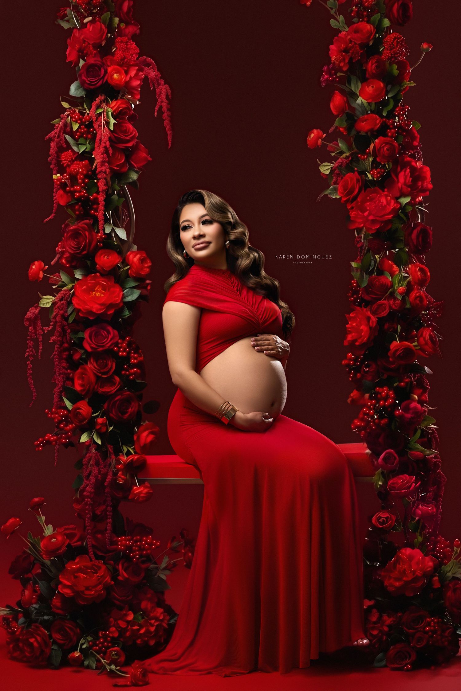 Artistic maternity portrait surrounded by colorful flowers and natural elements in romantic setting.