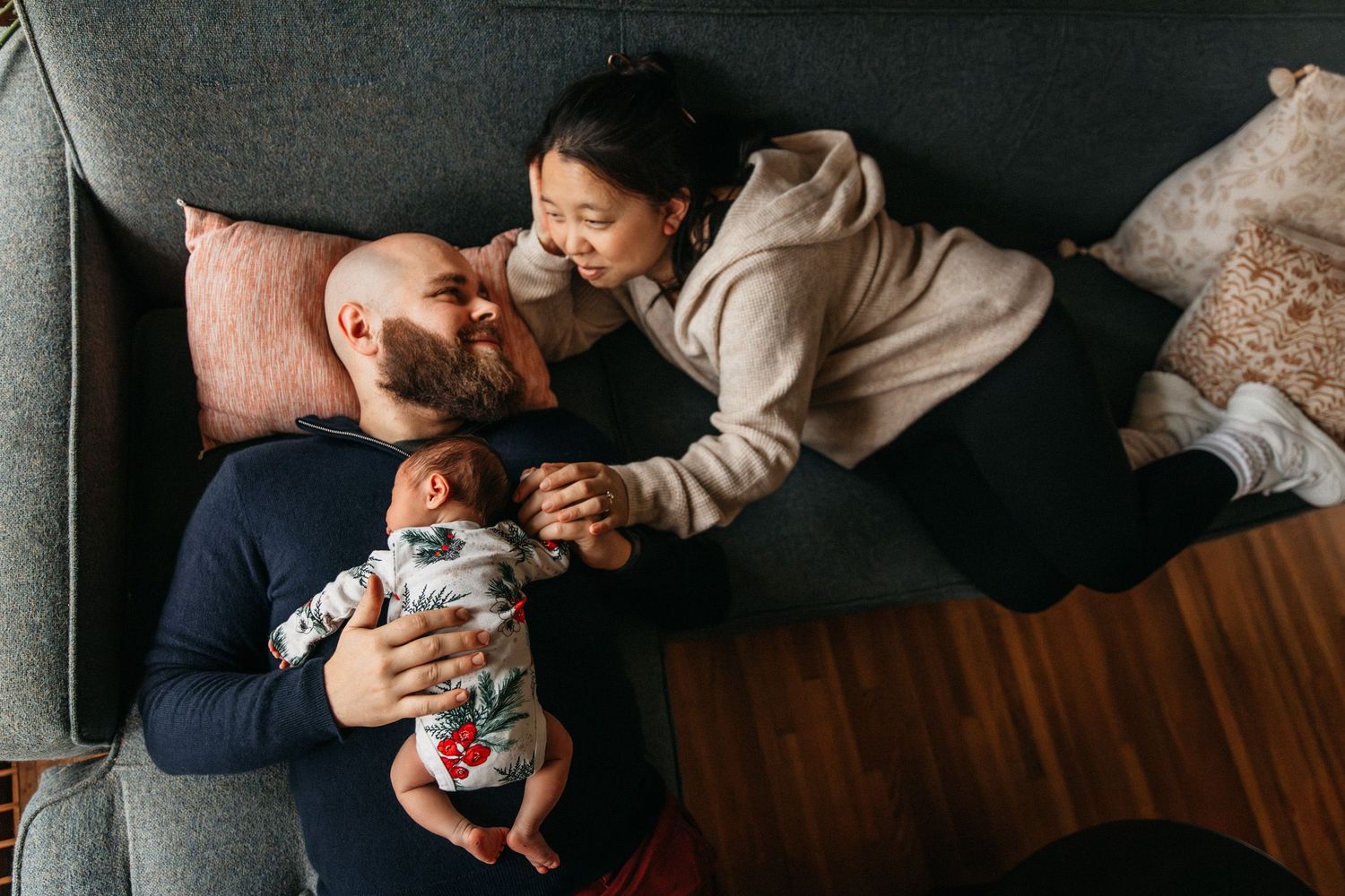 Documentary family photo of a couple cuddling on the couch with their newborn baby at their home in Minneapolis, MN