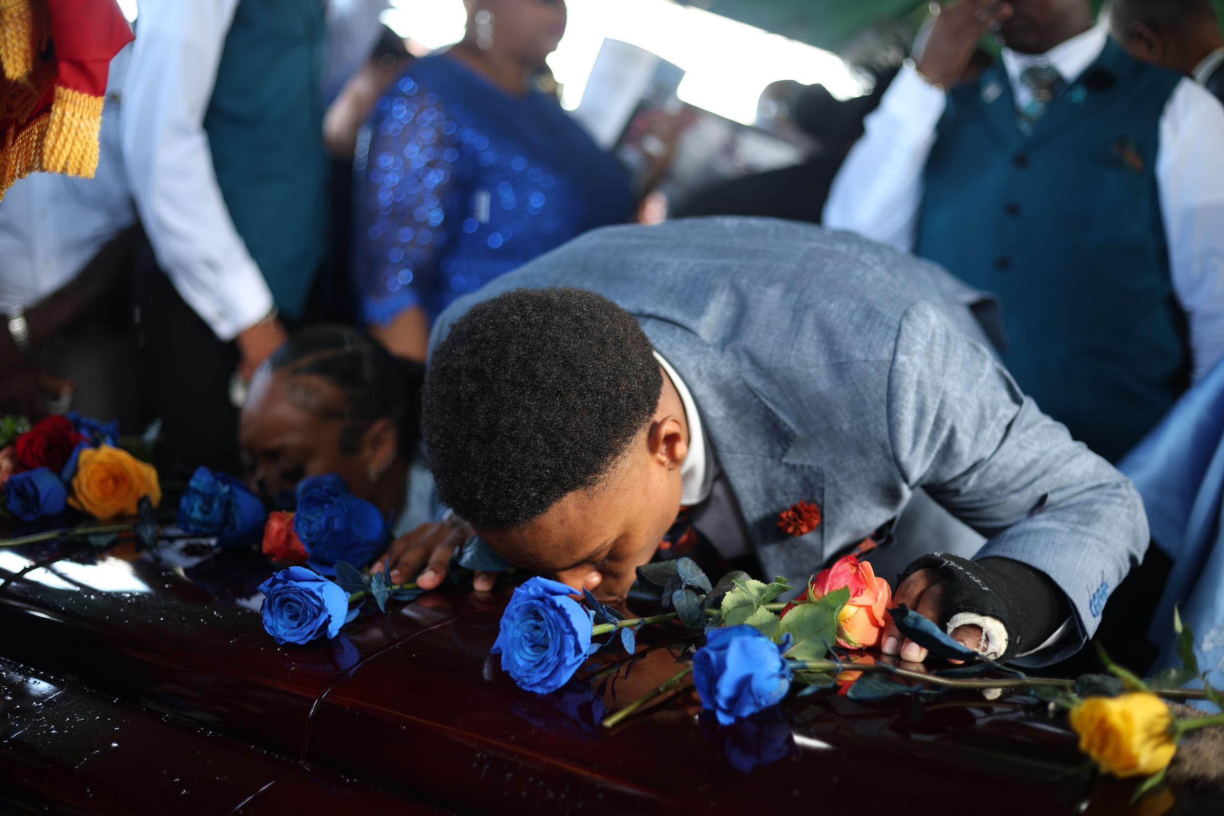 Blue and yellow flowers being placed during a memorial ceremony.