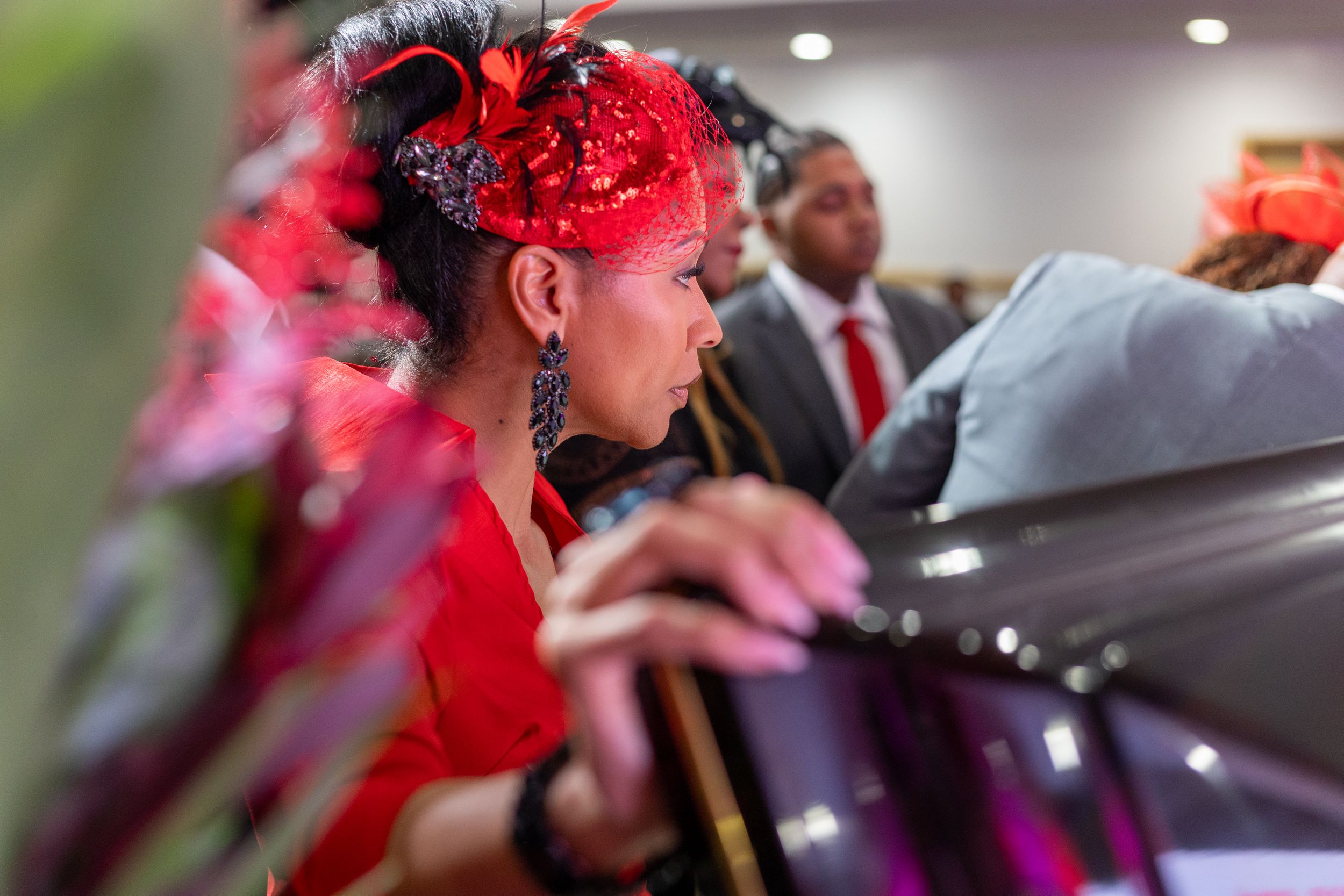 Row of caskets adorned with bright red floral arrangements and red fabric draping.