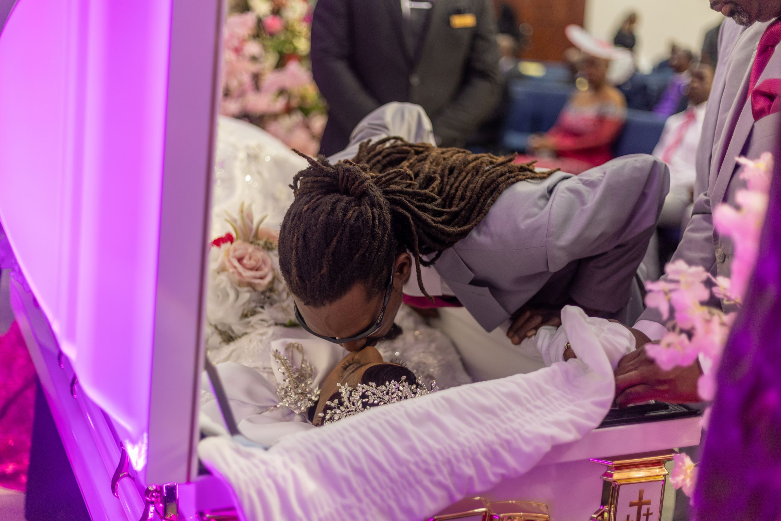 Memorial service setting with pink lighting and floral arrangements.