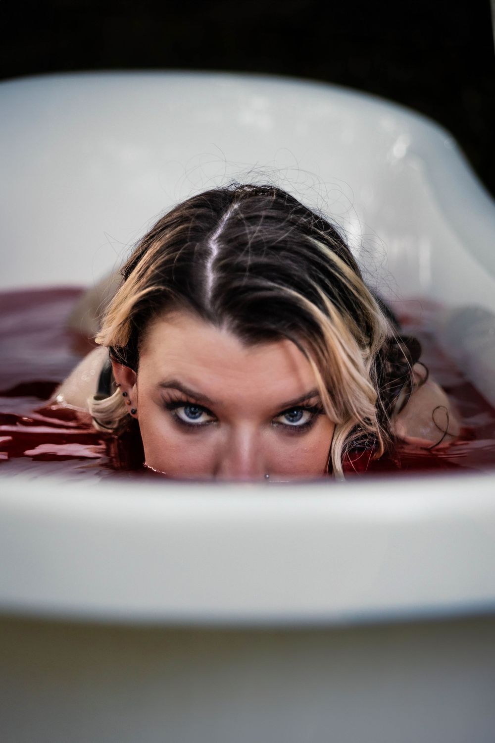 A woman poses seductively in a red bath.
