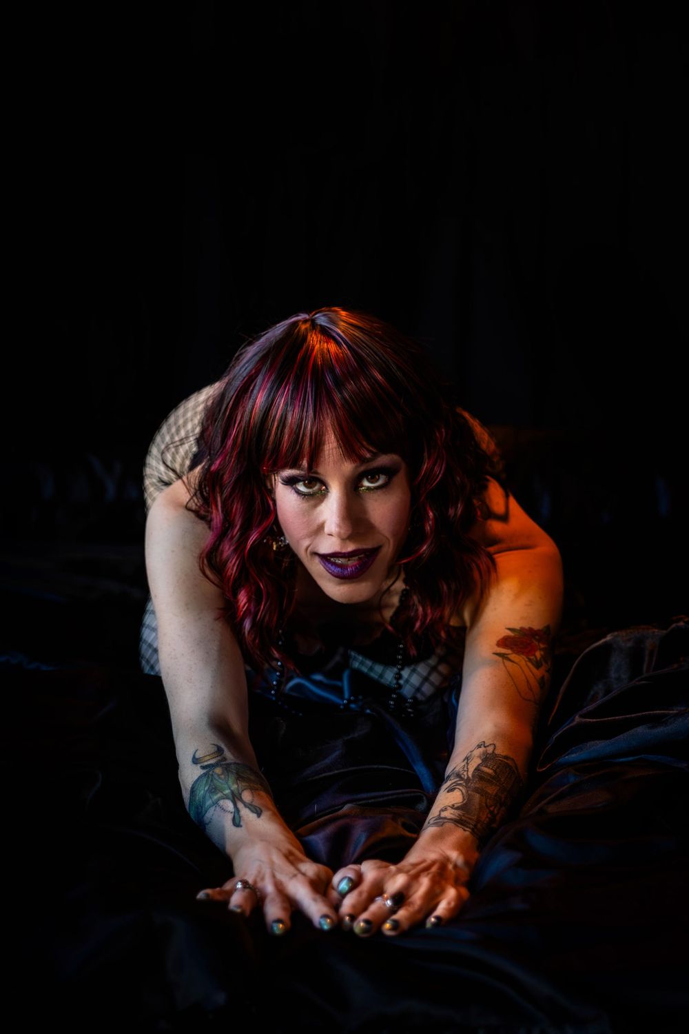 A woman with dark hair poses on a bed in a boudoir studio.