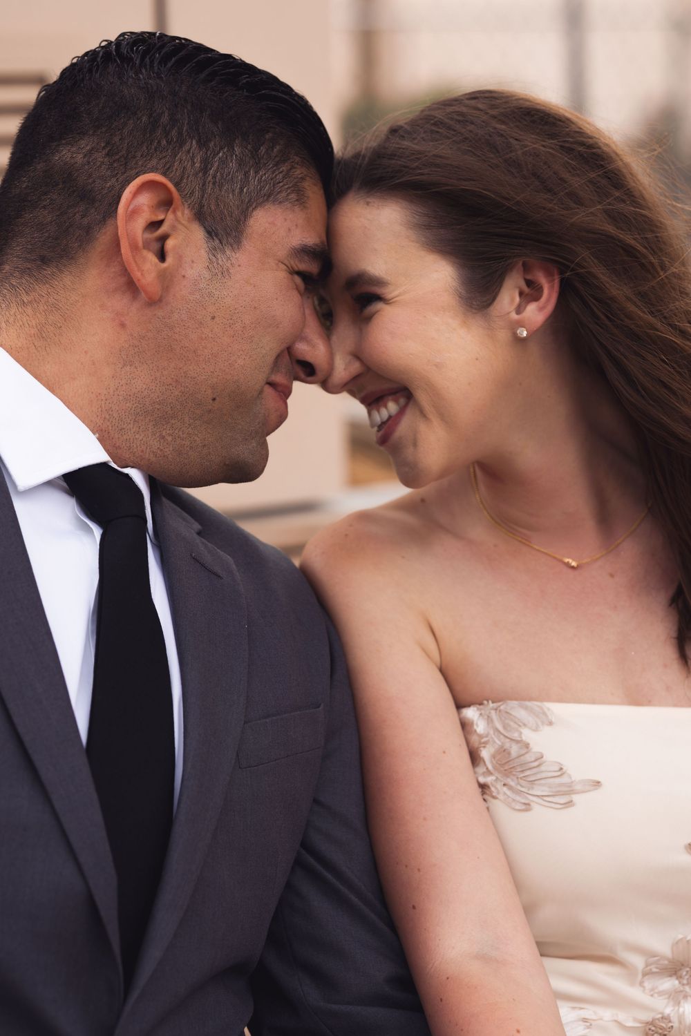 Bride and groom touching foreheads and smiling at each other on their wedding day.