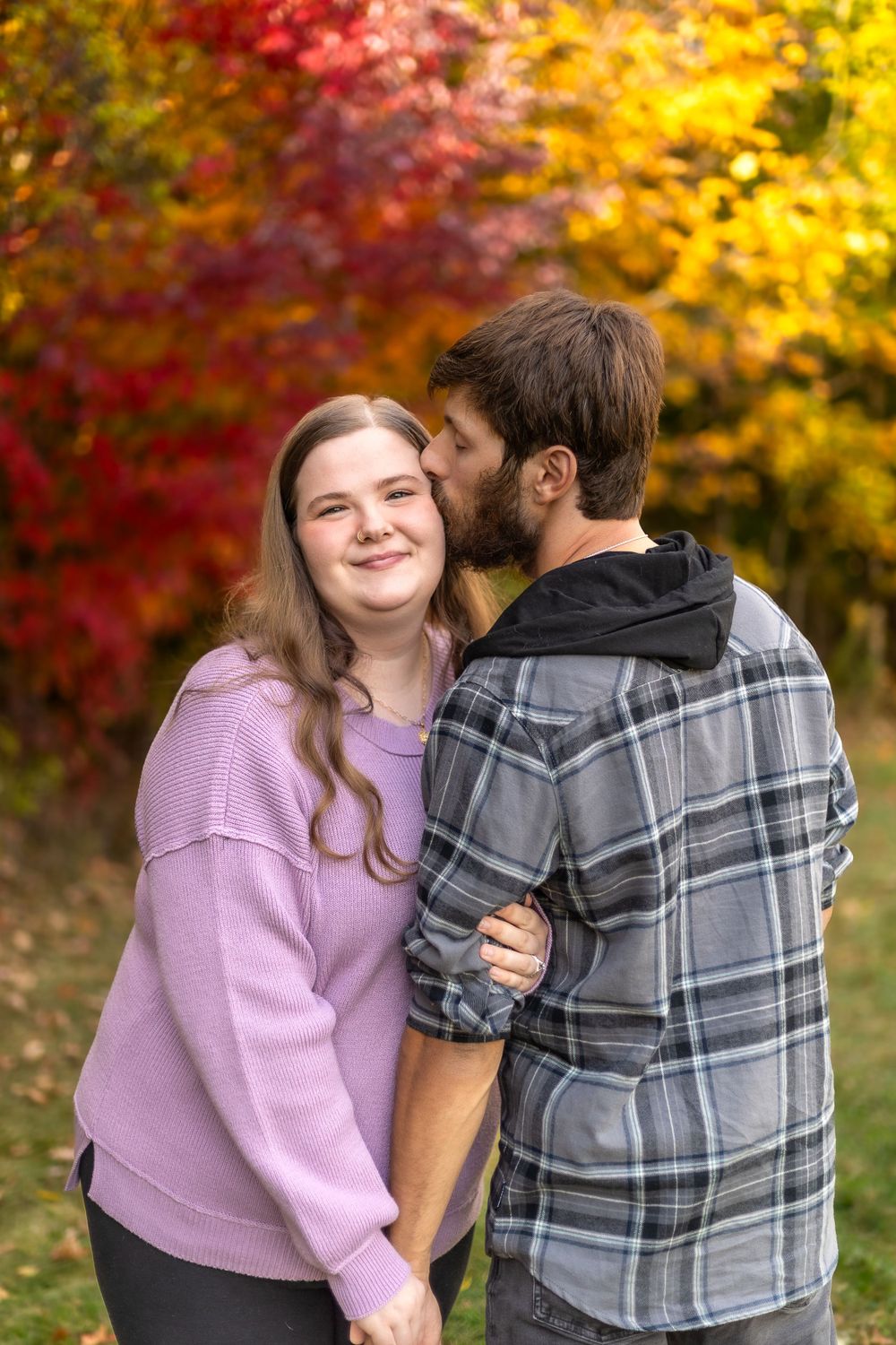 A tender moment captured between a couple against colorful fall foliage.