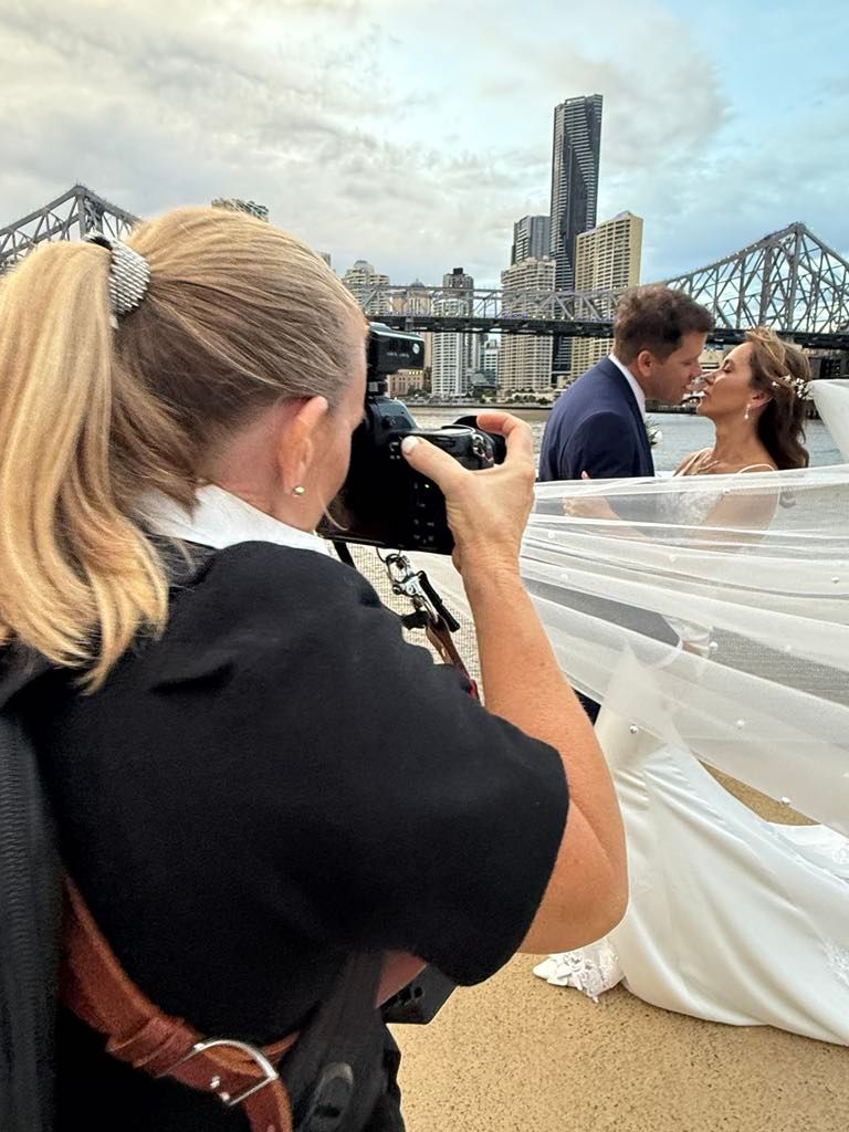 Wedding photographer captures a romantic moment between newlyweds with Brisbane's Story Bridge in background.