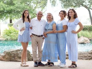 A group in coordinated light blue outfits poses together by a pool in a garden setting.