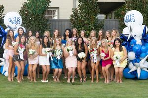 Large group of people sitting together outdoors wearing coordinated outfits for a group photo session.