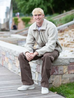 Person in a cozy fleece jacket sits casually on stone steps outdoors on a cloudy day.