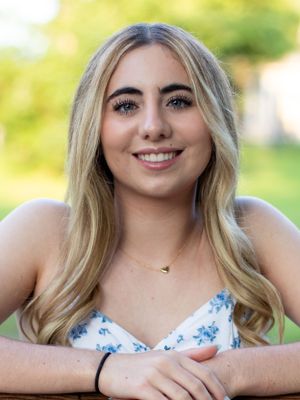 Portrait showing someone in a blue and white floral top smiling at camera.