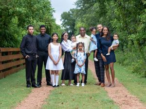 Extended family poses together on outdoor path surrounded by greenery.