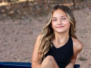 Portrait of young person in black tank top with long wavy hair.