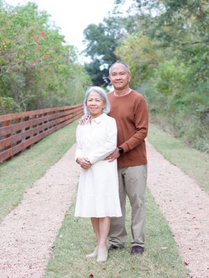Couple standing together on rustic path wearing brown and white sweaters.