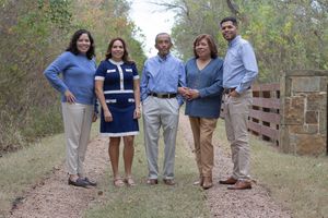 A group in casual clothing poses together on a dirt path surrounded by autumn foliage and trees.