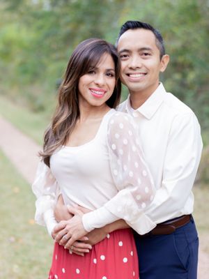 Couple embracing on nature path wearing white formal attire.
