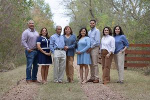 A group of people standing together outdoors on a dirt path surrounded by trees and greenery.