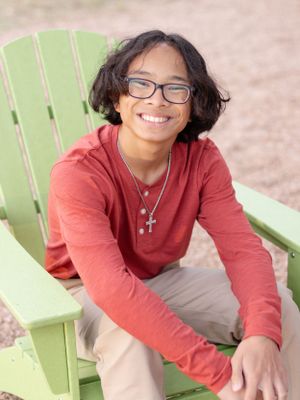 Person relaxing in lime green Adirondack chair wearing red sweater and glasses.